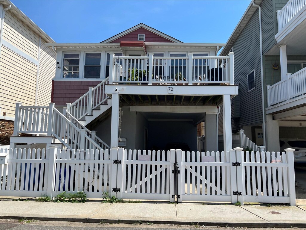 exterior space with stairway, a gate, a deck, and a fenced front yard