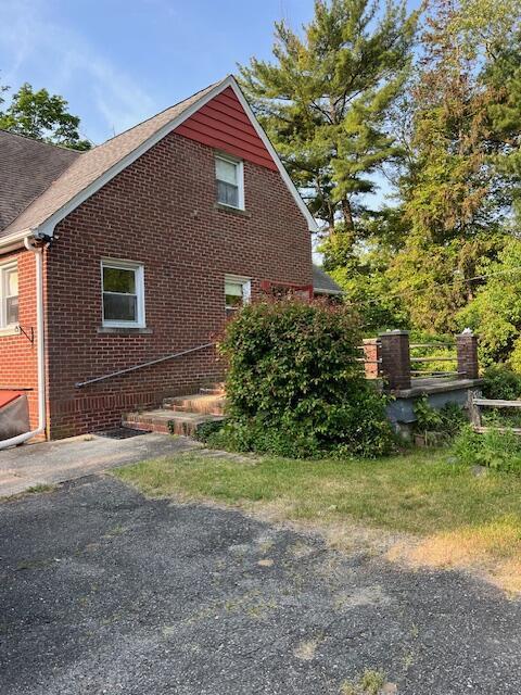 view of home's exterior with roof with shingles and brick siding