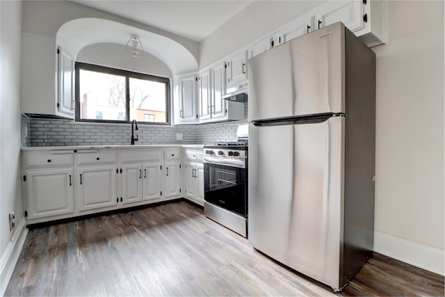 48-42 64th St, Woodside, NY 11377 - kitchen with a sink, stainless steel appliances, under cabinet range hood, backsplash, and white cabinetry