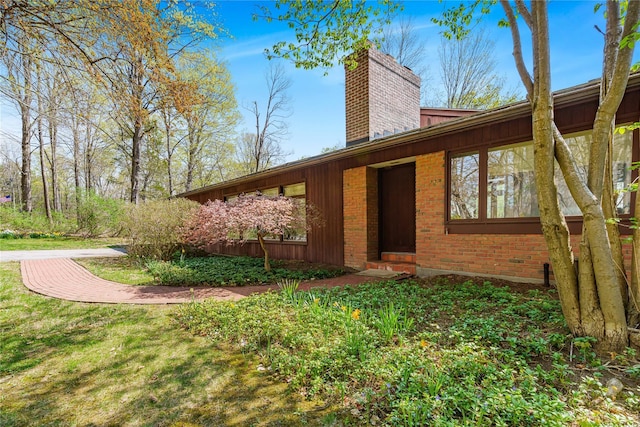view of home's exterior featuring a chimney and brick siding
