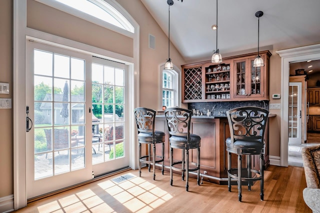 bar with tasteful backsplash, wood finished floors, visible vents, pendant lighting, and a bar