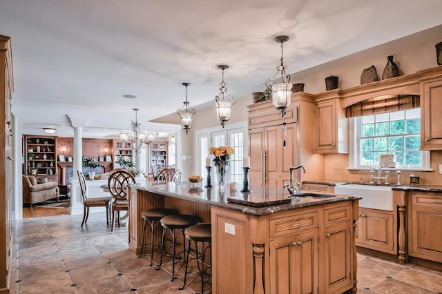 kitchen with dark stone countertops, a breakfast bar area, tasteful backsplash, a sink, and a center island with sink