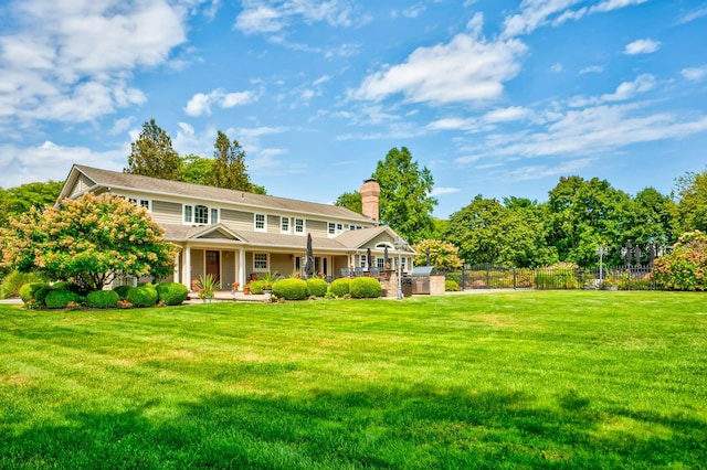 view of front facade with a front yard, fence, and a chimney