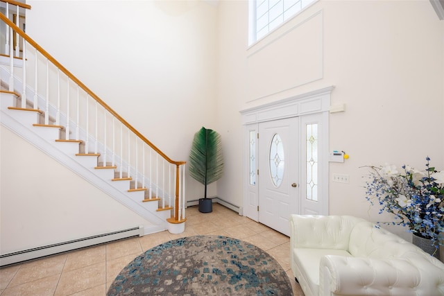 tiled foyer entrance with stairway, a baseboard heating unit, and a high ceiling