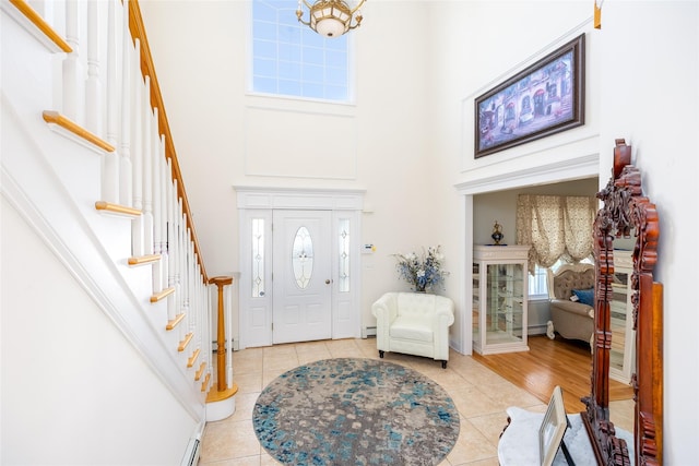 entrance foyer with baseboards, stairs, a high ceiling, and light tile patterned flooring