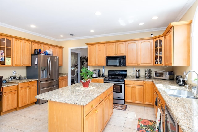 kitchen with light tile patterned floors, a sink, appliances with stainless steel finishes, and a kitchen island