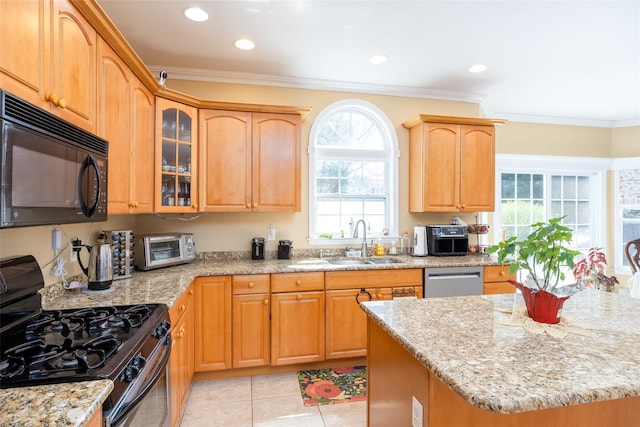 kitchen with glass insert cabinets, light stone counters, stainless steel appliances, a sink, and crown molding