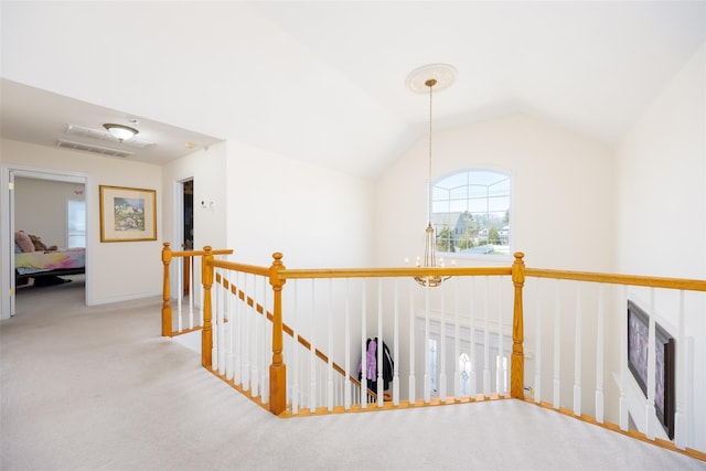 corridor with an upstairs landing, carpet floors, and vaulted ceiling