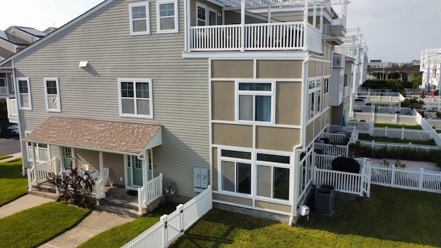 rear view of property featuring covered porch, fence private yard, a lawn, and central air condition unit