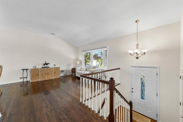 entryway featuring vaulted ceiling, dark wood-type flooring, a chandelier, and baseboards