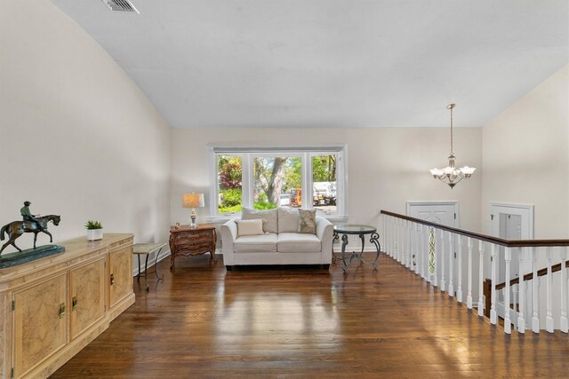 living room featuring wood finished floors, a chandelier, and vaulted ceiling