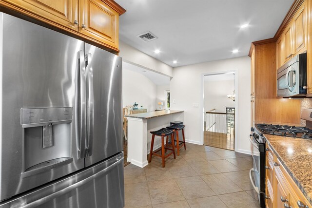 kitchen featuring stainless steel appliances, light stone counters, light tile patterned floors, recessed lighting, and a kitchen bar