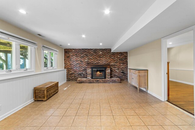 unfurnished living room with a brick fireplace, light tile patterned floors, recessed lighting, and brick wall