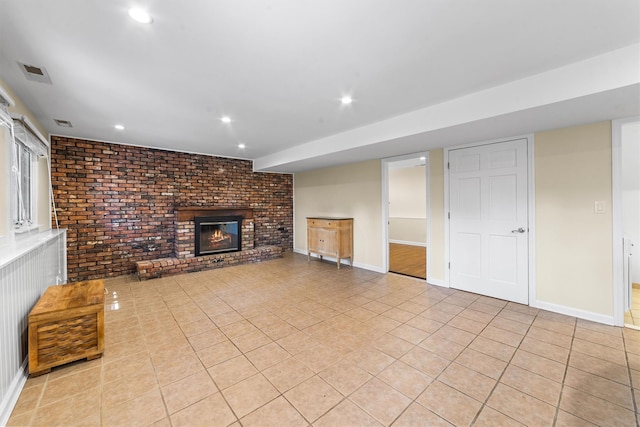 unfurnished living room featuring brick wall, light tile patterned flooring, a brick fireplace, recessed lighting, and baseboards