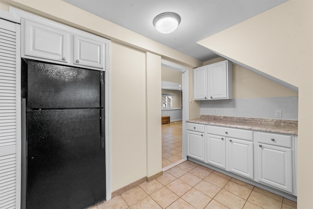 kitchen featuring freestanding refrigerator, white cabinetry, light tile patterned floors, and baseboards