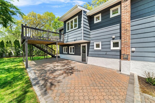 view of home's exterior with a deck, a patio, a yard, and stairs