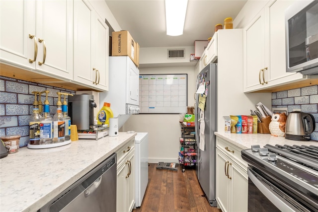 1203 E Broadway Unit G11, Hewlett, NY 11557 - kitchen with visible vents, white cabinetry, dark wood finished floors, appliances with stainless steel finishes, and stacked washer / drying machine