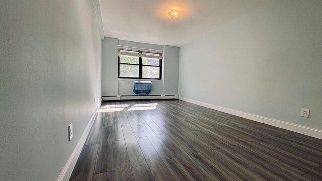 40 Stoner Ave Unit 1S, Great Neck, NY 11021 - unfurnished room with dark wood-type flooring, baseboards, and a baseboard heating unit