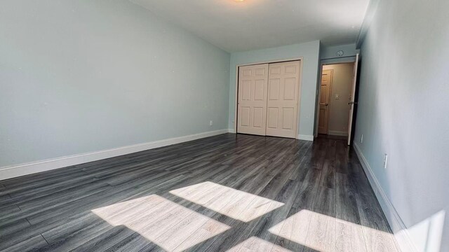 40 Stoner Ave Unit 1S, Great Neck, NY 11021 - unfurnished bedroom with dark wood-style flooring, baseboards, and a closet