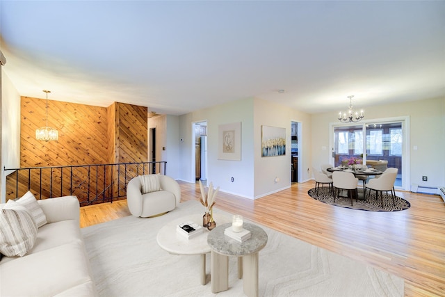 living room with baseboards, wooden walls, wood finished floors, and a notable chandelier