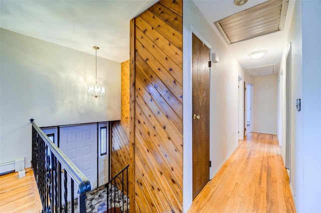 hall with visible vents, attic access, light wood finished floors, and an upstairs landing