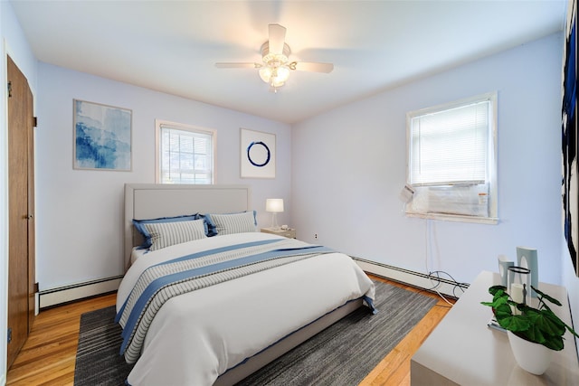 bedroom with baseboard heating, a ceiling fan, and light wood-style flooring