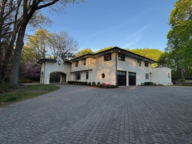 view of front facade with curved driveway, an attached garage, and stucco siding