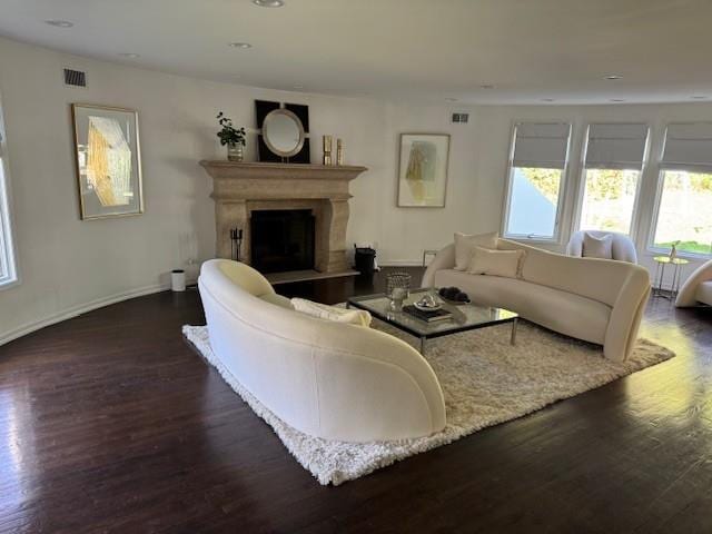 living area featuring visible vents, a fireplace with raised hearth, wood finished floors, and recessed lighting