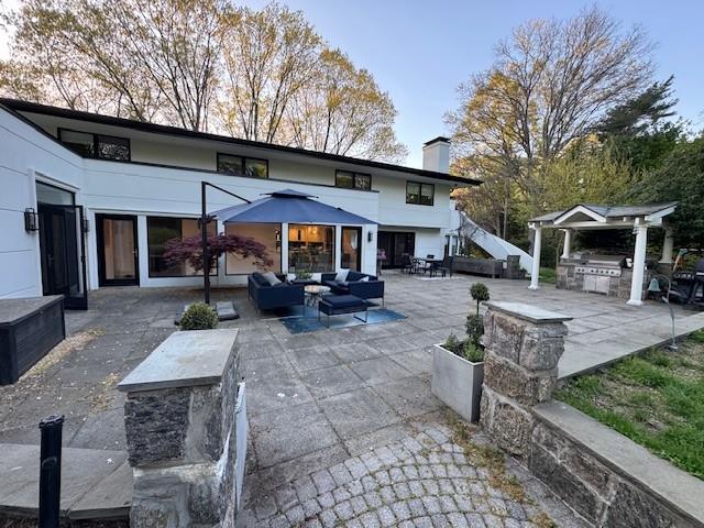 rear view of house with area for grilling, a chimney, a patio area, and outdoor lounge area