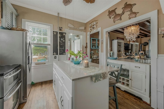 46 Satinwood Rd, Rocky Point, NY 11778 - kitchen with appliances with stainless steel finishes, wood finished floors, white cabinets, a chandelier, and a kitchen island