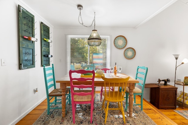 dining area with ornamental molding, baseboards, and light wood-style floors