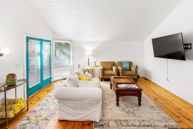 living room featuring baseboards, light wood-style flooring, and lofted ceiling