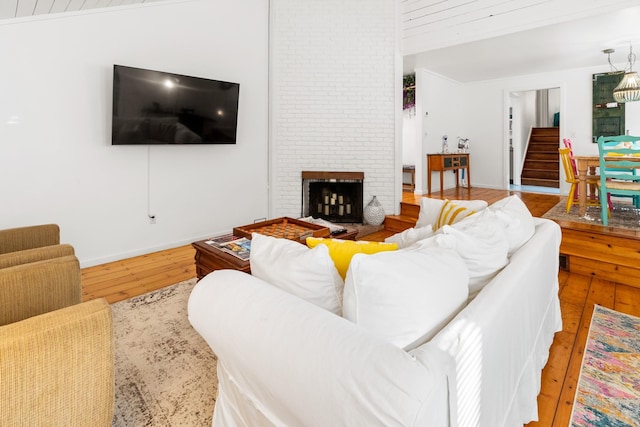 living area with hardwood / wood-style flooring, a fireplace, baseboards, stairway, and lofted ceiling
