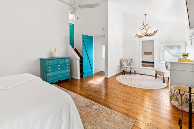bedroom with baseboards, high vaulted ceiling, hardwood / wood-style flooring, and a notable chandelier