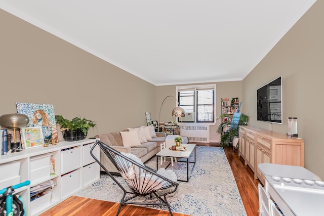 living room with ornamental molding, radiator, and wood finished floors