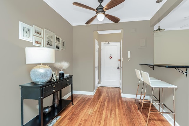 entrance foyer with baseboards, ornamental molding, light wood finished floors, and a ceiling fan