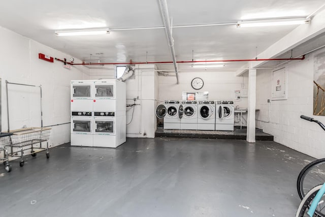 garage featuring washer and dryer, stacked washing maching and dryer, and concrete block wall