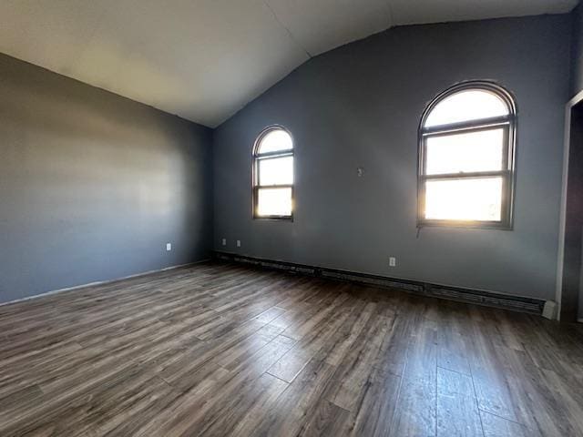 unfurnished room featuring dark wood finished floors, baseboard heating, and lofted ceiling