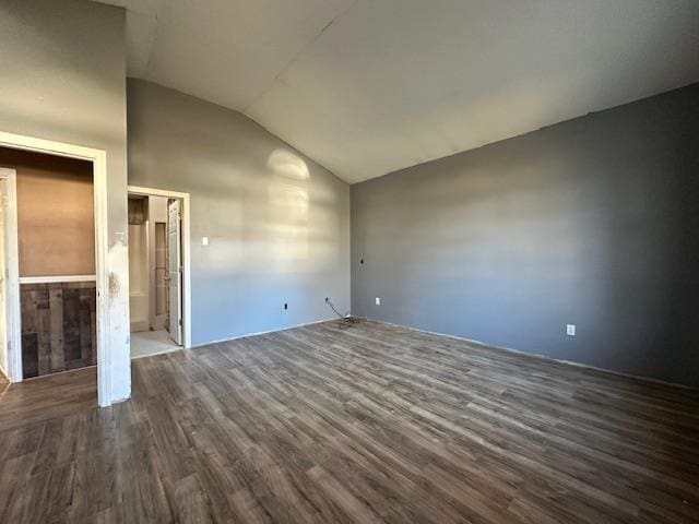 unfurnished bedroom featuring dark wood-type flooring, ensuite bath, and vaulted ceiling