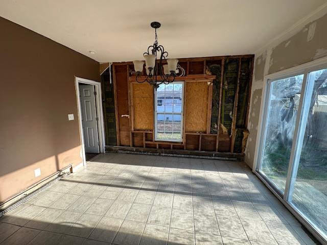 unfurnished dining area featuring a healthy amount of sunlight, a notable chandelier, and tile patterned flooring