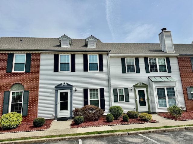 townhome / multi-family property featuring a chimney and uncovered parking
