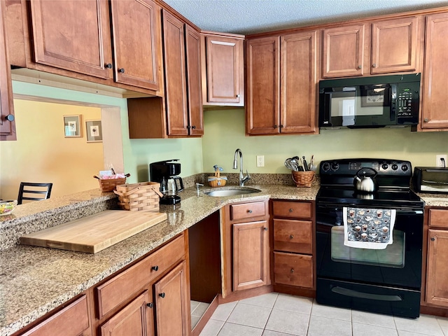 kitchen with light stone countertops, a sink, brown cabinets, light tile patterned floors, and black appliances