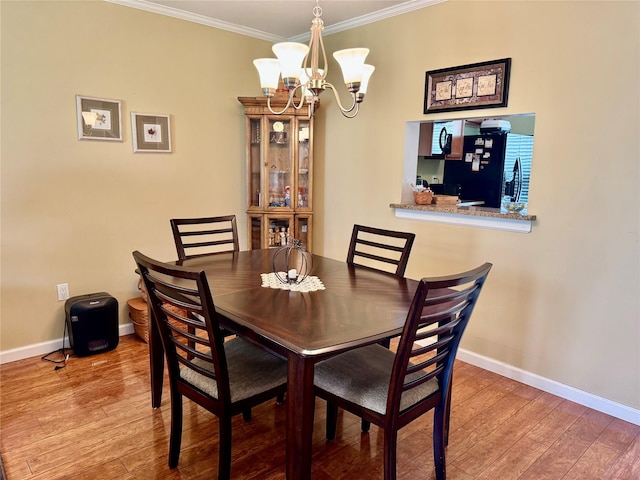 dining room with an inviting chandelier, wood finished floors, crown molding, and baseboards
