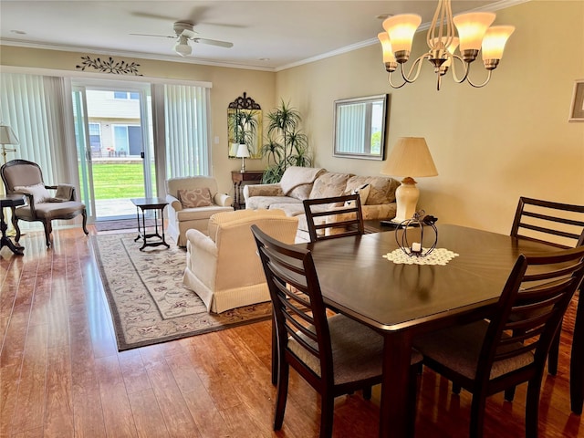 dining space featuring hardwood / wood-style flooring, ornamental molding, and ceiling fan with notable chandelier
