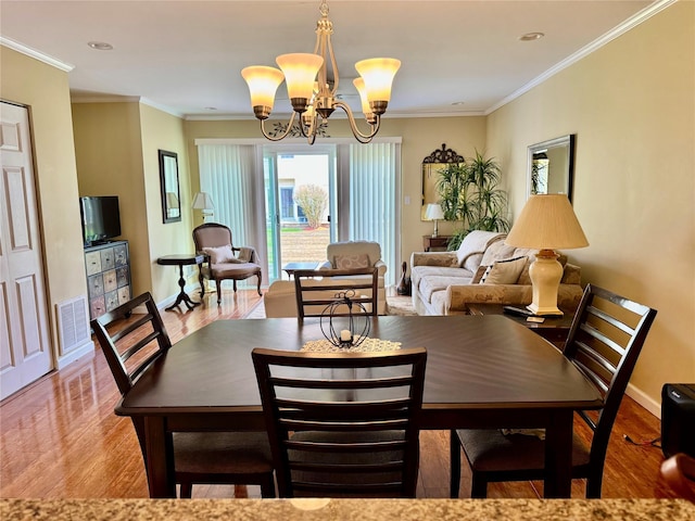 dining area with a chandelier, visible vents, wood finished floors, and ornamental molding