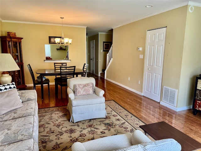living room featuring wood finished floors, an inviting chandelier, stairway, baseboards, and visible vents
