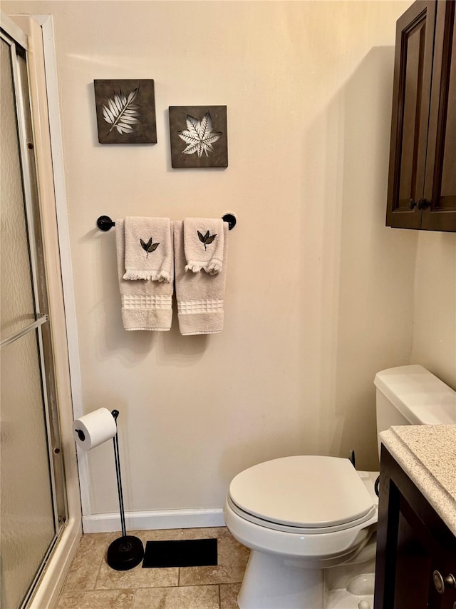 bathroom featuring a shower stall, vanity, tile patterned floors, toilet, and baseboards
