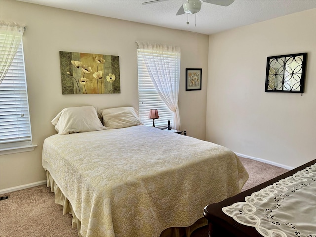 bedroom with carpet, ceiling fan, visible vents, and baseboards