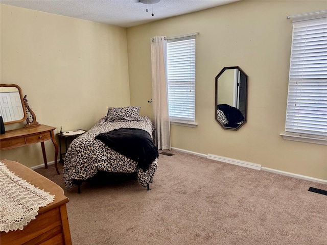 bedroom with carpet, visible vents, baseboards, and multiple windows