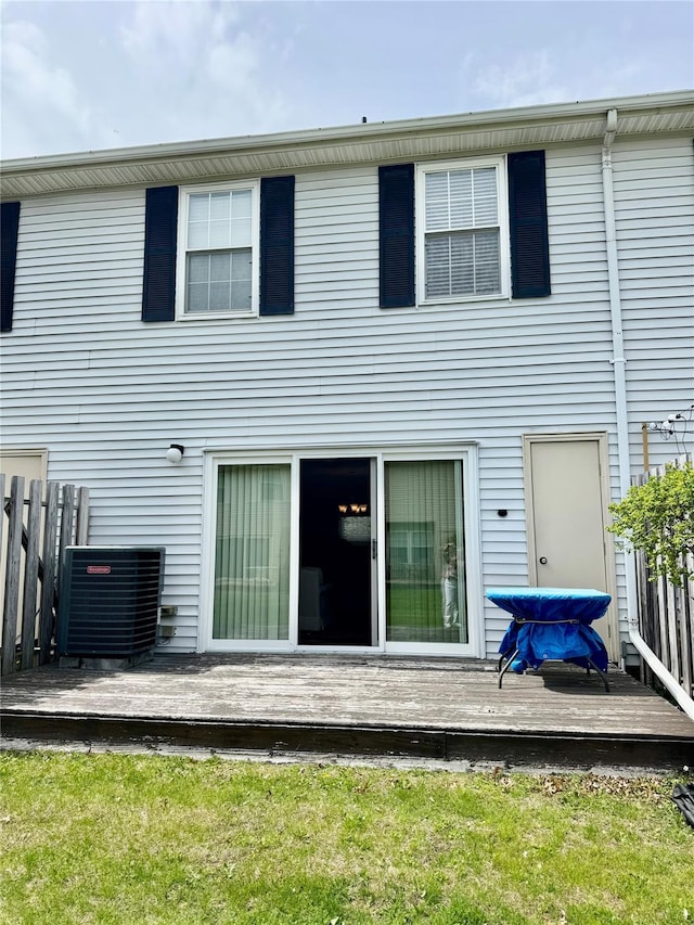 rear view of property with fence, a wooden deck, and cooling unit